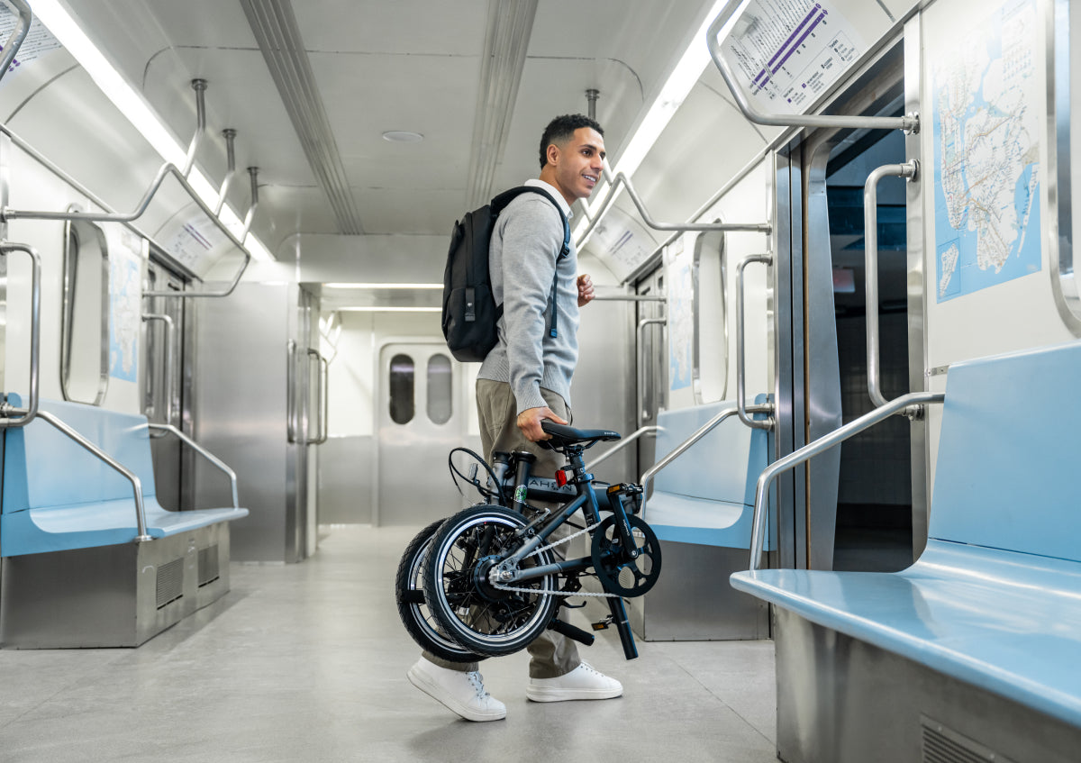 A man carries a folded DAHON bike through a subway train, demonstrating seamless multi-modal urban travel.