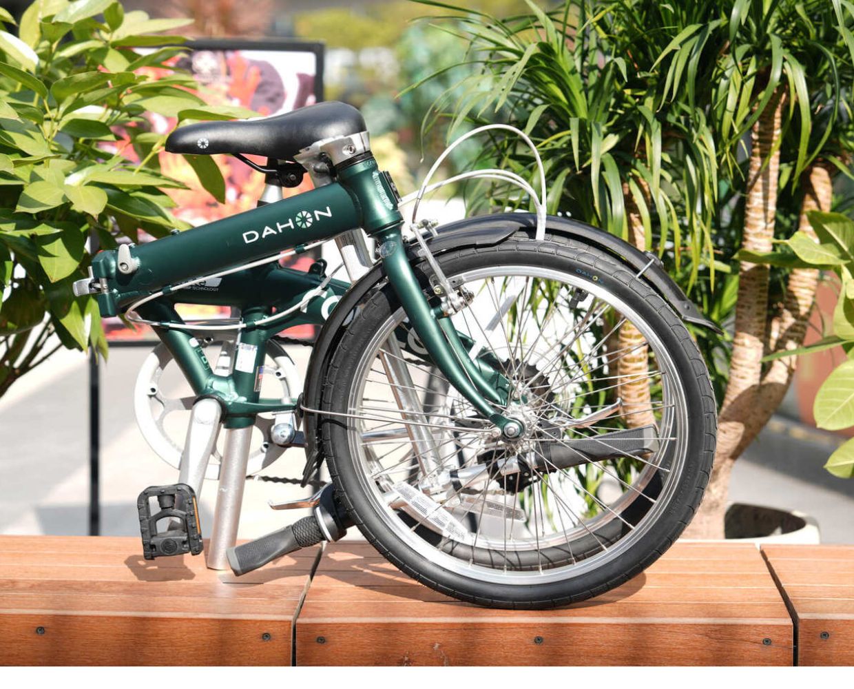 Dark green Dahon Route foldable bicycle with aluminum frame, black saddle and silver crankset, partially unfolded outdoors.