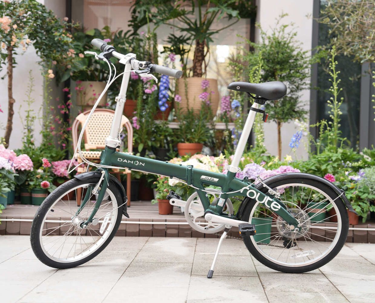 Dark green Dahon Route foldable bicycle with aluminum frame, black fenders, and multi-gear system, displayed outdoors.